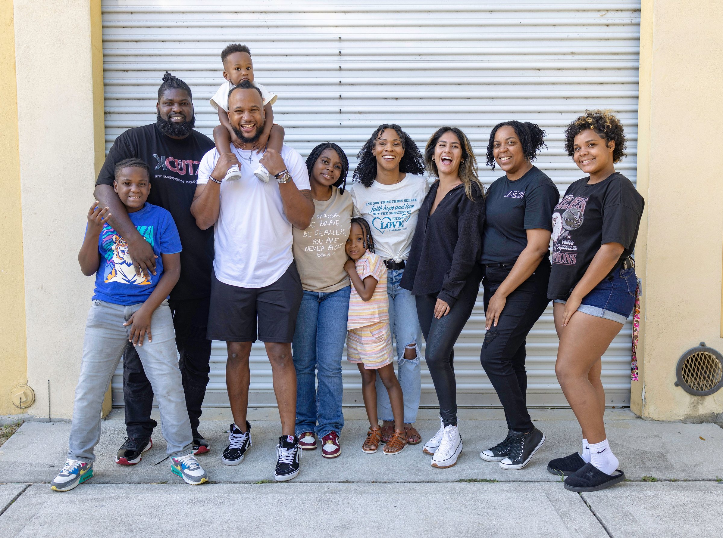 A multigenerational family smiling together in front of their home